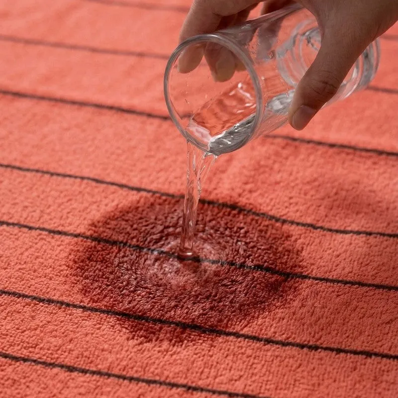 Water being poured onto an orange striped bath towel