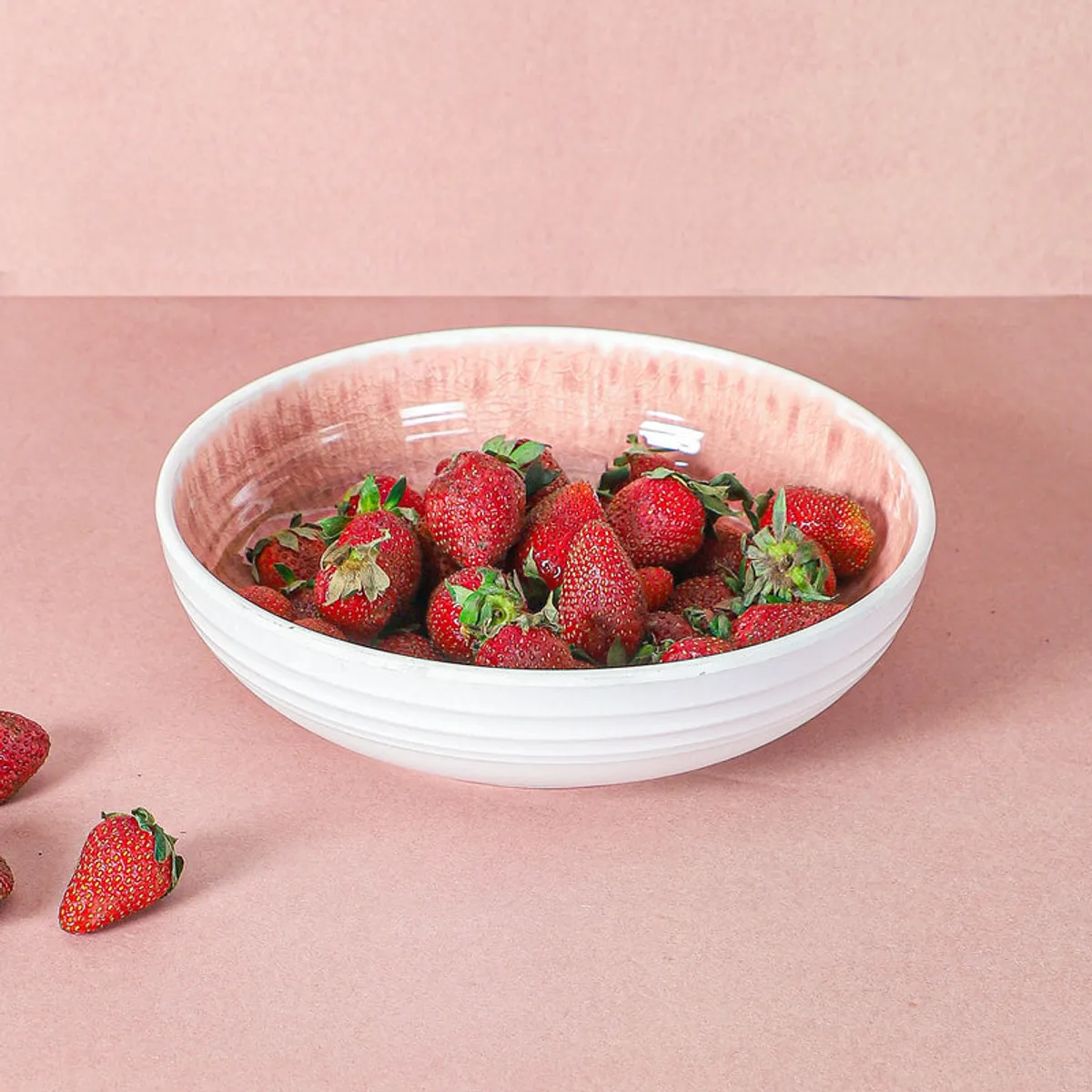 White and pink serving bowl of strawberries photographed from the front