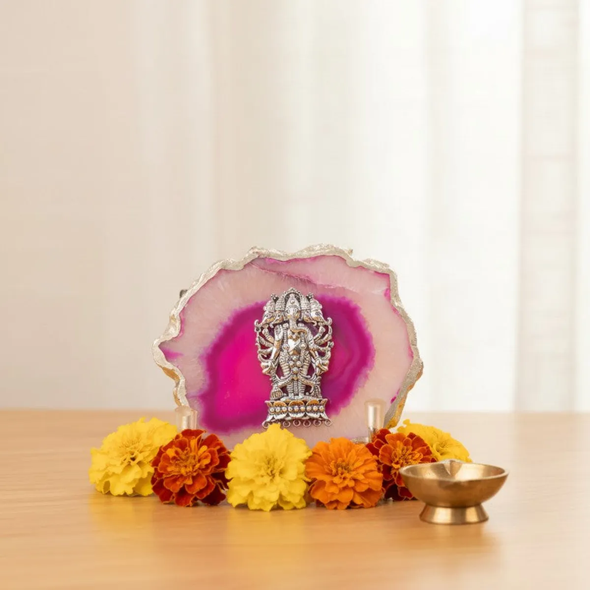 Pink agate Ganesha showpiece arranged with marigold flowers on a tabletop.