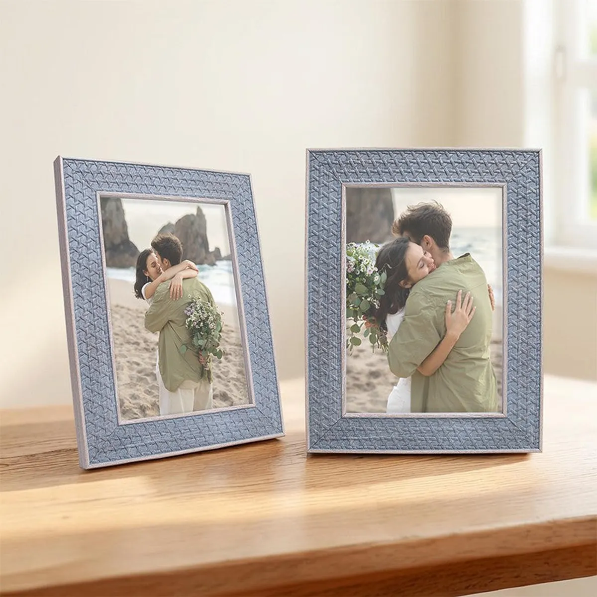 Pair of blue-grey textured rectangular photo frames on a sunlit wooden surface.