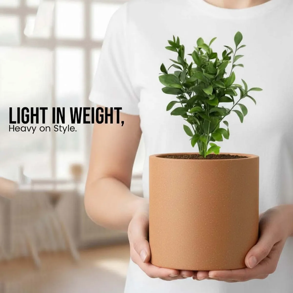 Person holding a brown cylindrical planter with a leafy plant.