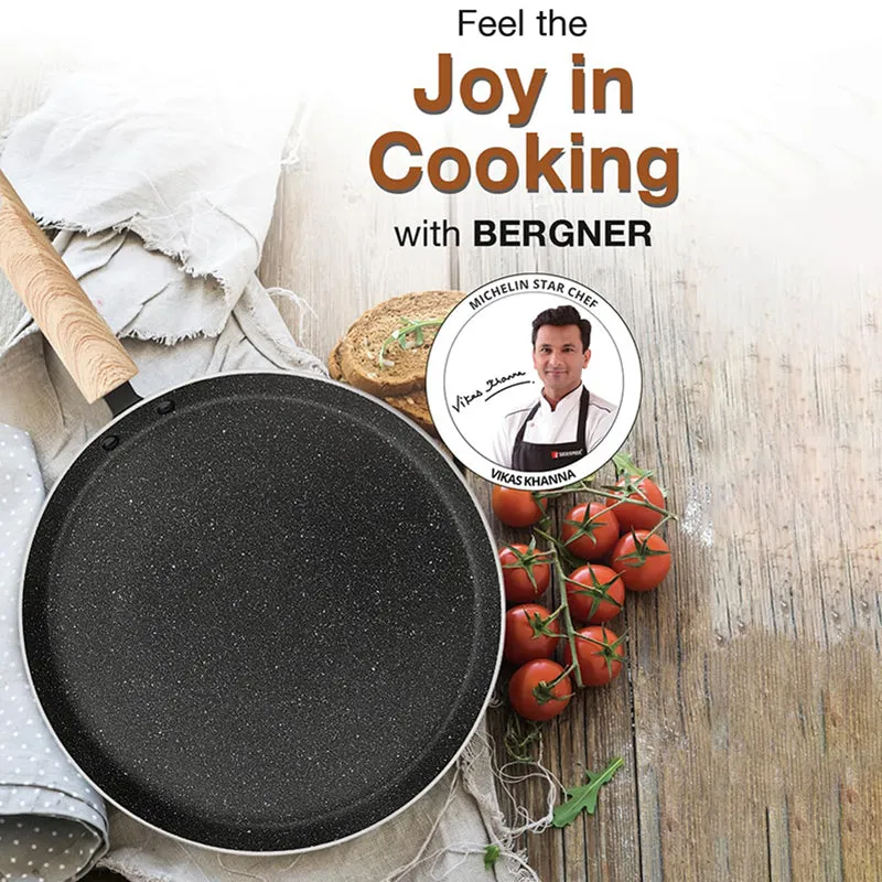 Black round dosa tawa with a light wooden-finish handle on a styled kitchen surface