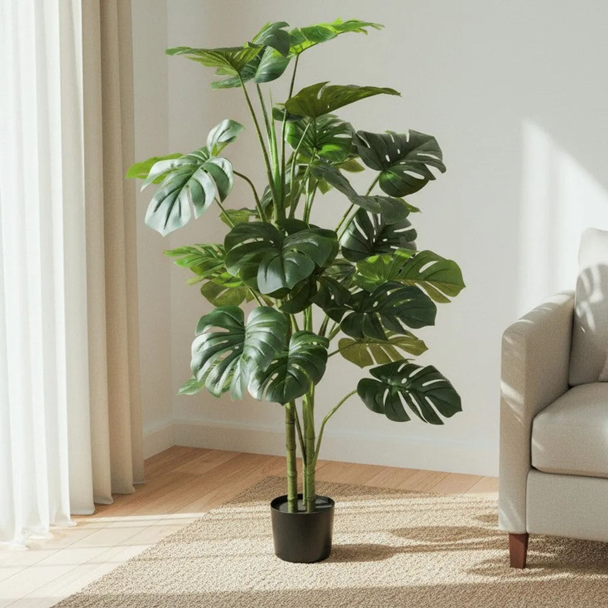 Tall artificial monstera plant with layered green leaves in a black pot beside a sofa