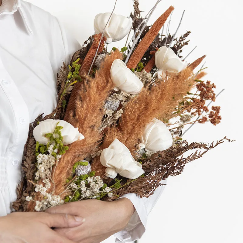 Close-up of a dried bouquet with white flowers, brown leaves and rust grasses