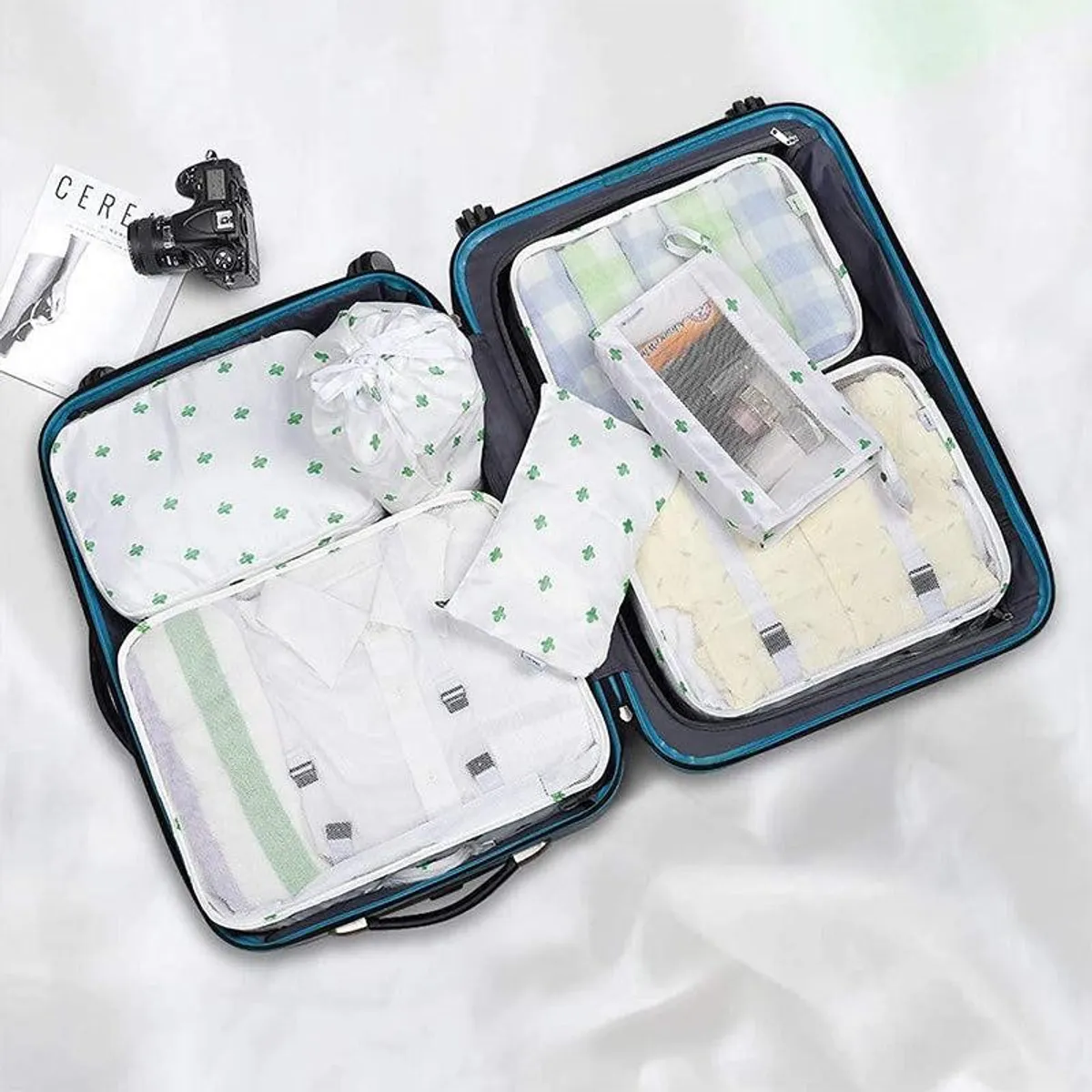 Cactus-print organisers arranged inside two open suitcases with folded clothing.