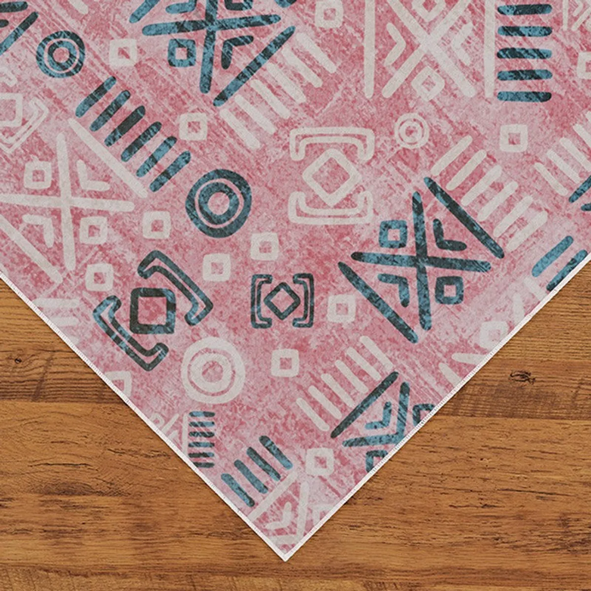 Corner view of pink patterned carpet on wooden floor