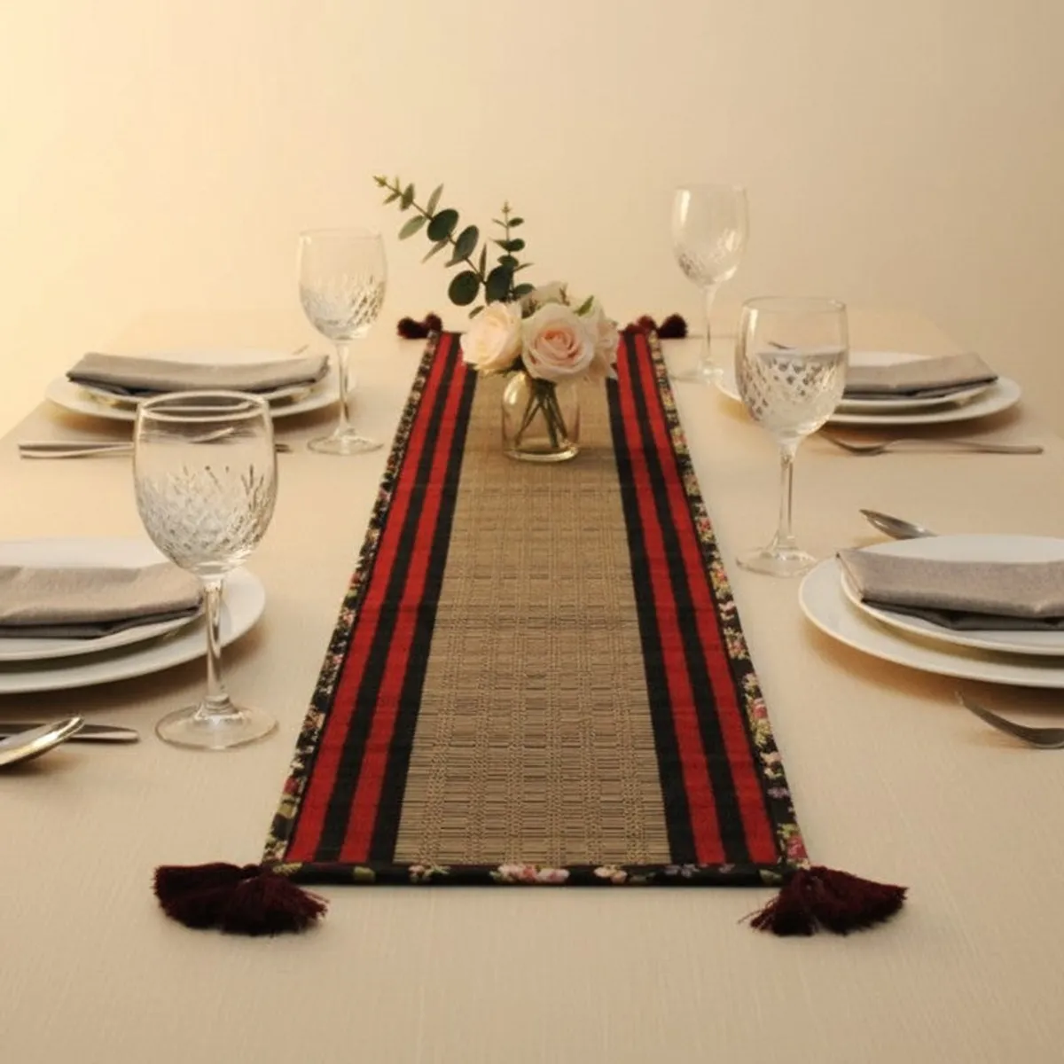 Striped black and red table runner with beige centre styled on a dining table
