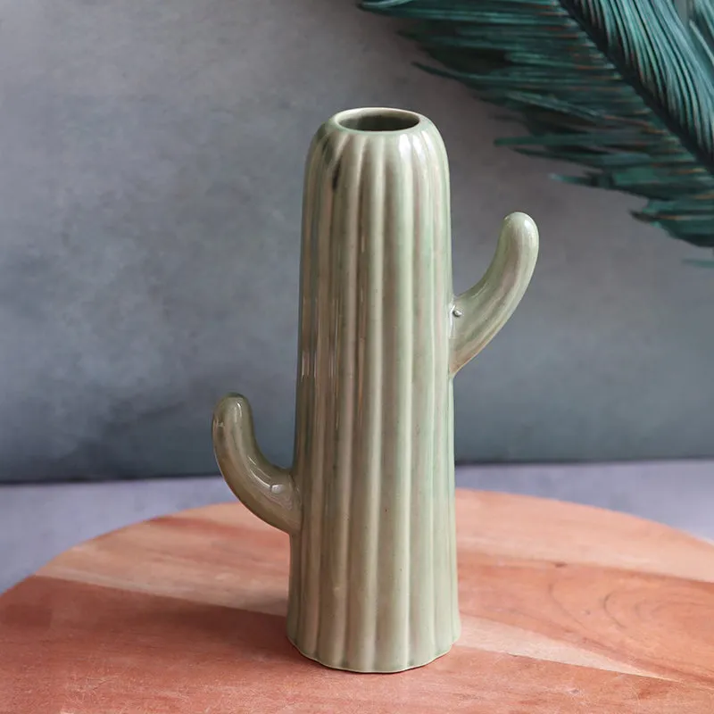 Close view of a dark green cactus-shaped ceramic vase on a wooden surface
