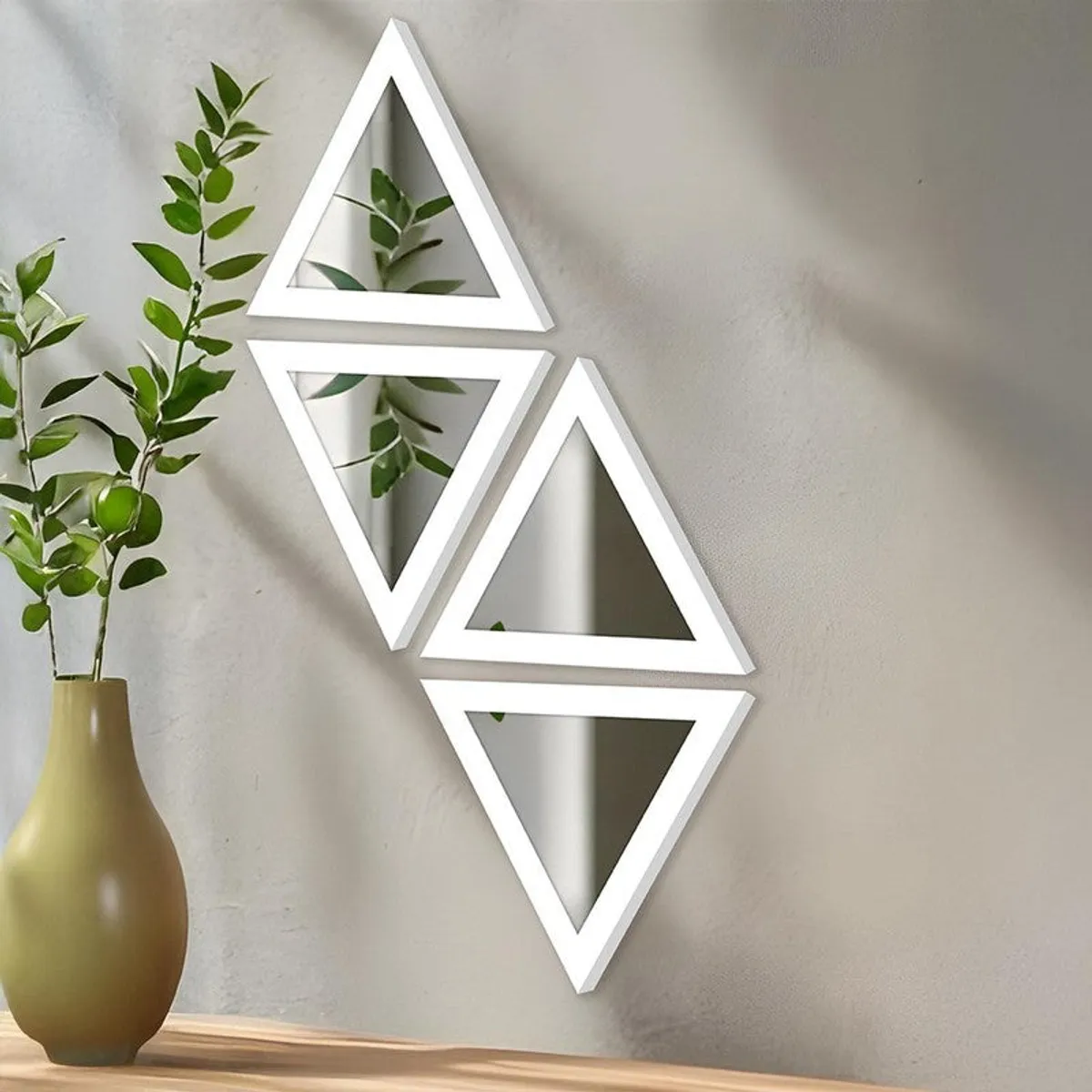 Set of four white triangular wall mirrors arranged vertically on a light wall