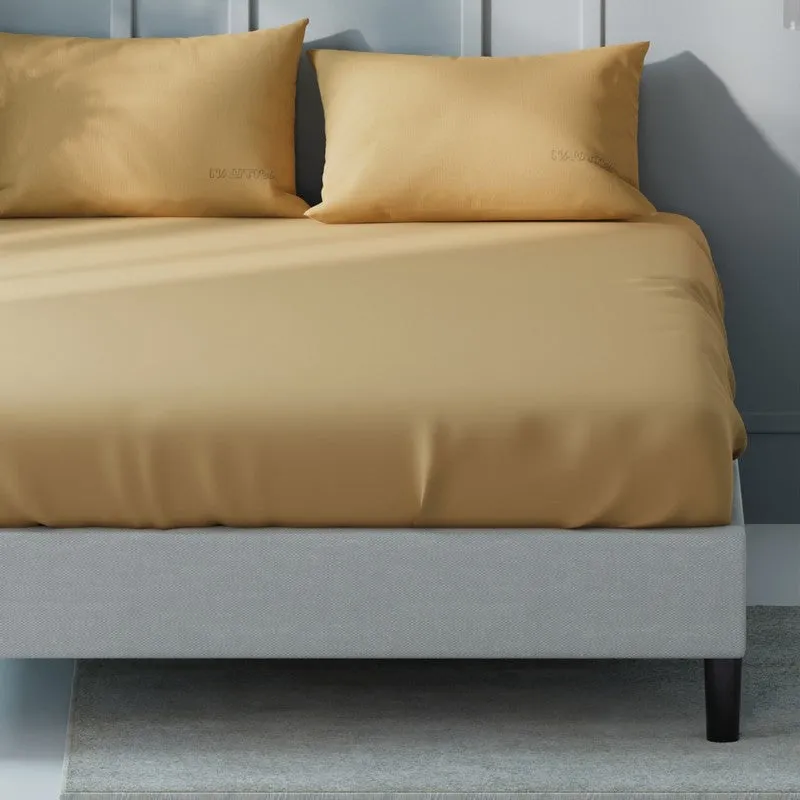 Close view of the smooth mustard-yellow bedsheet draped over the bed