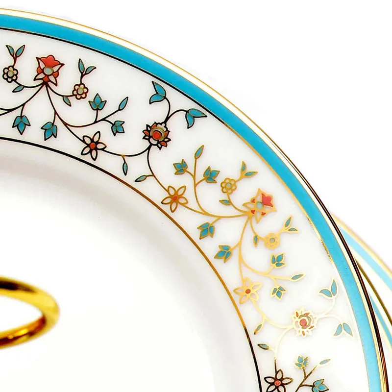 Close-up of white porcelain plate with blue rim, gold border and colourful floral detailing