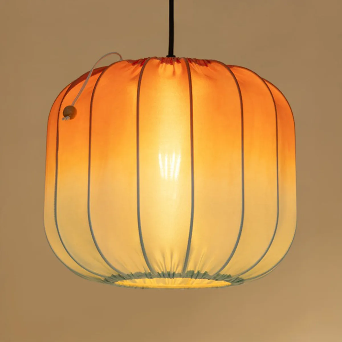 Bottom view of the warm glowing orange pendant lamp with ribbed shade