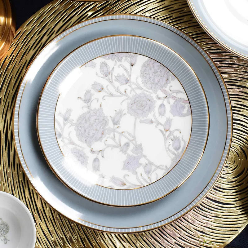 Grey floral dinner plate with concentric borders and gold edging on a decorative gold mat
