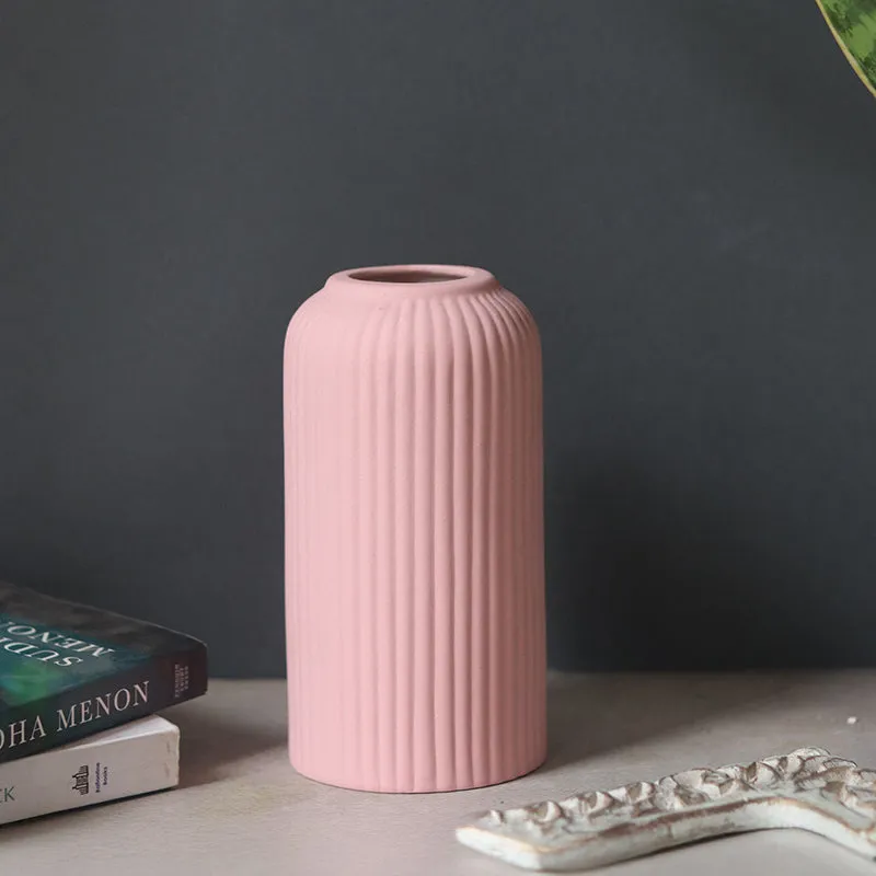 Pink ribbed vase styled on a tabletop with stacked books and a decorative tray