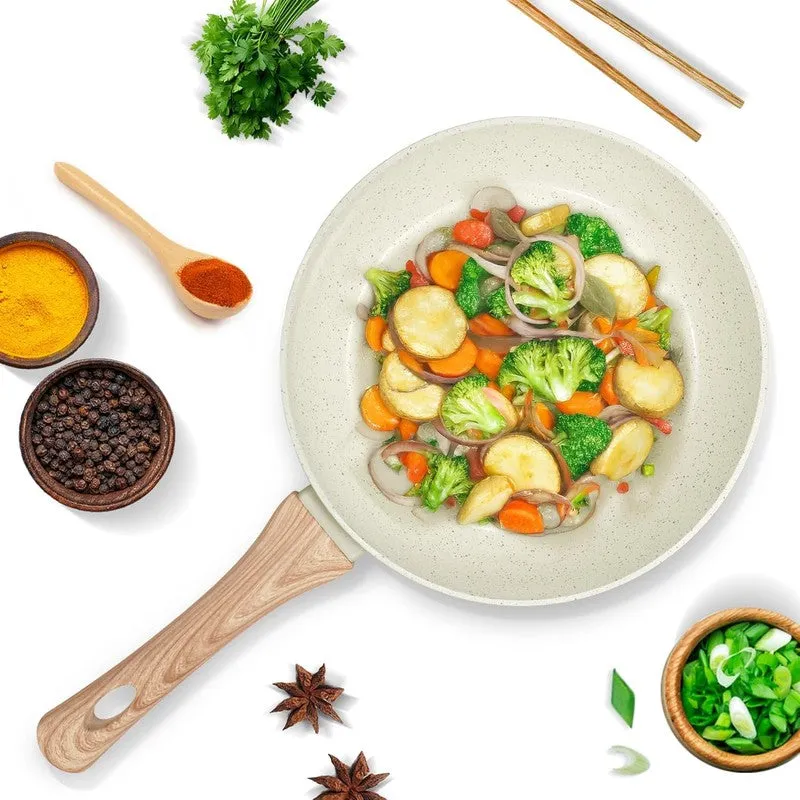 Top view of white speckled frying pan with vegetables and wood-look handle
