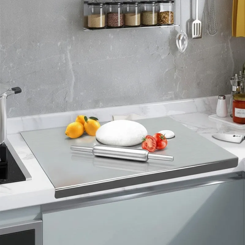 Steel rolling pin and board set on a kitchen counter with dough and tomatoes