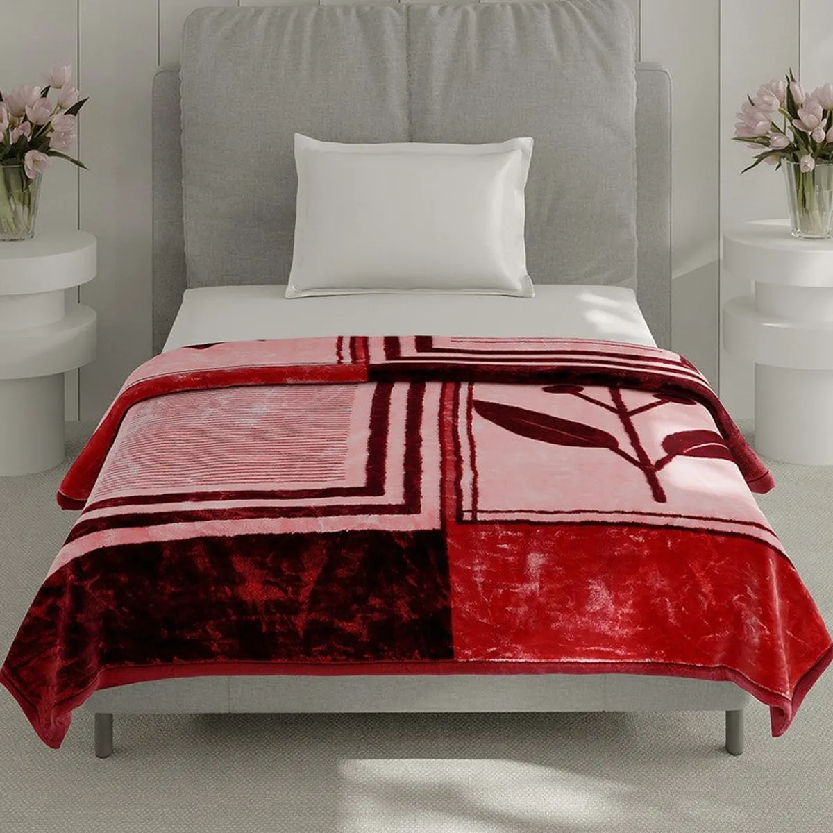 Front view of a maroon and pink geometric blanket on a bed