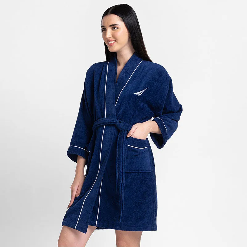Angled view of navy blue bath robe with white piping and pockets