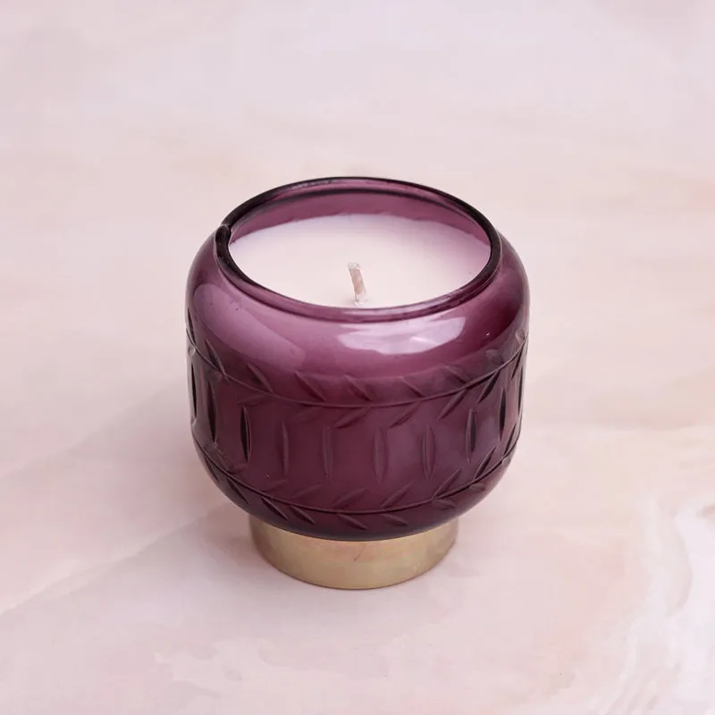 Purple glass candle with white wax and embossed leaf pattern