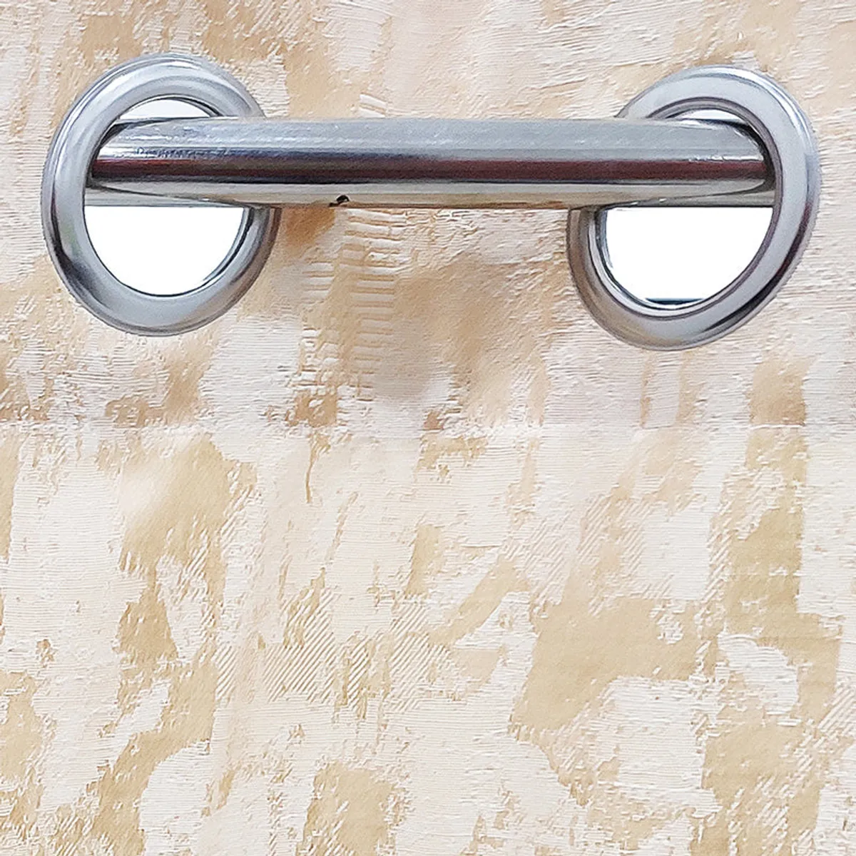 Close-up of silver eyelets set into the beige curtain fabric