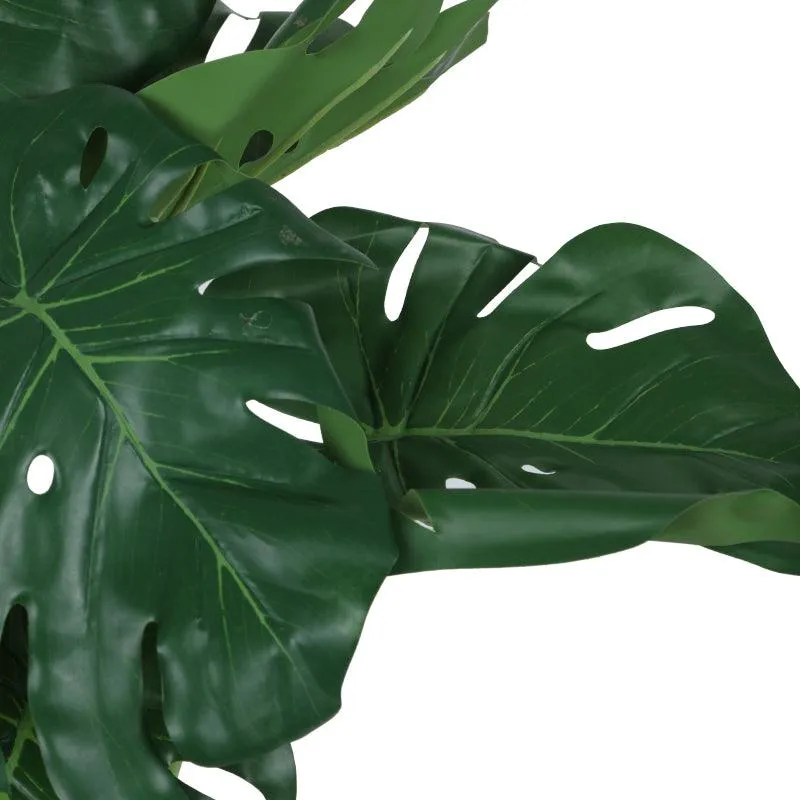 Close-up of glossy dark green artificial Monstera leaves with split detailing