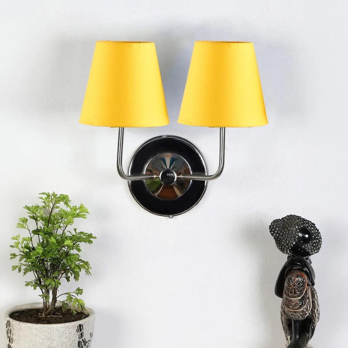 Wall-mounted lamp with yellow shades and round steel backplate on a white wall