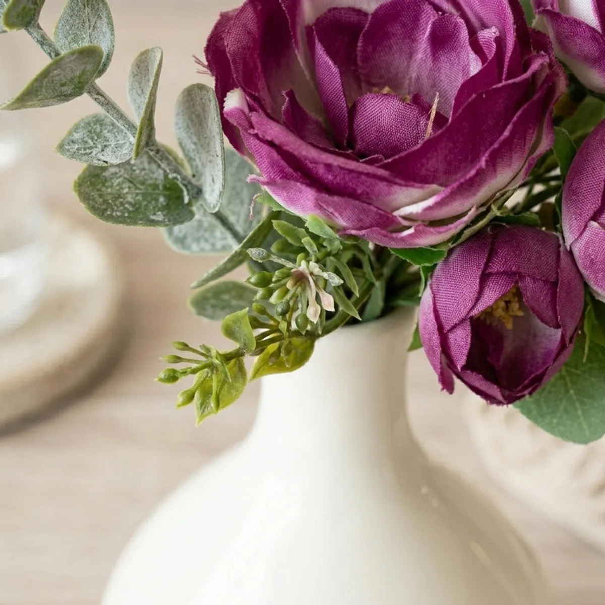 Close-up of the white vase neck with purple flowers and green stems