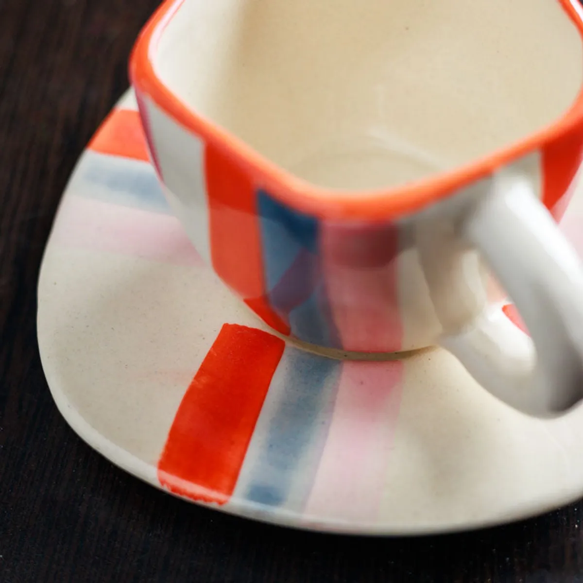 Close-up of a glossy striped ceramic cup and matching saucer