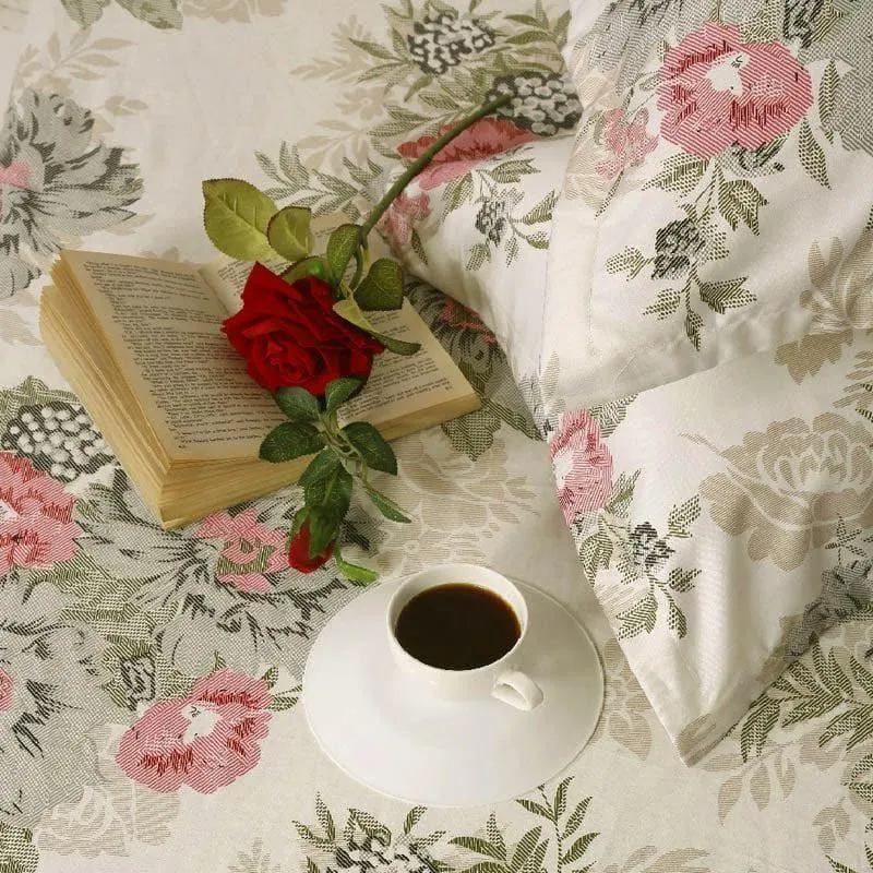 Detailed view of the floral bedsheet with pillow cover, book, rose and coffee cup