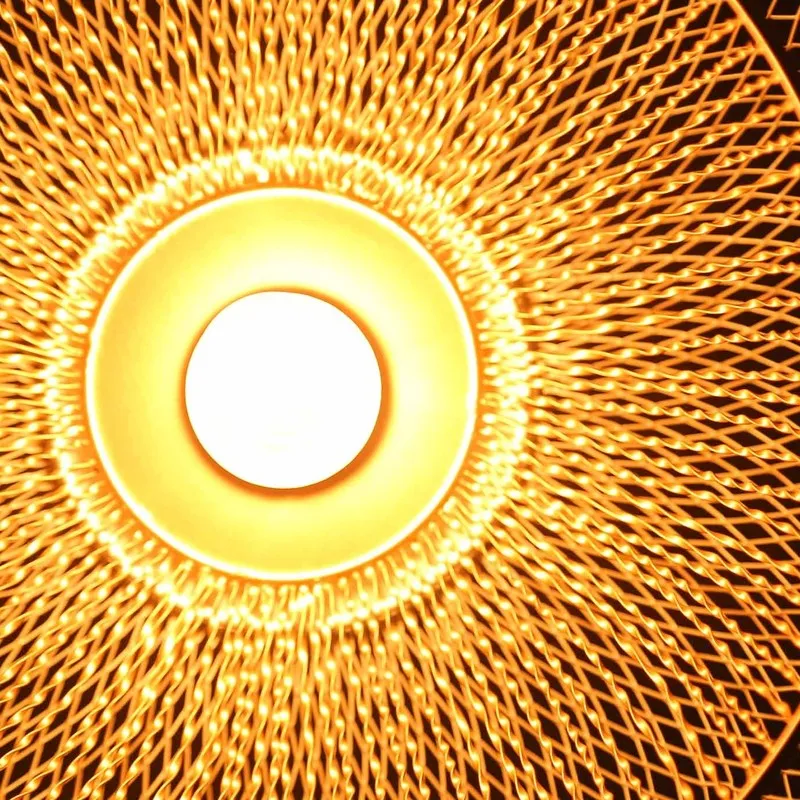Close-up of glowing bulb inside the lamp's gold mesh shade