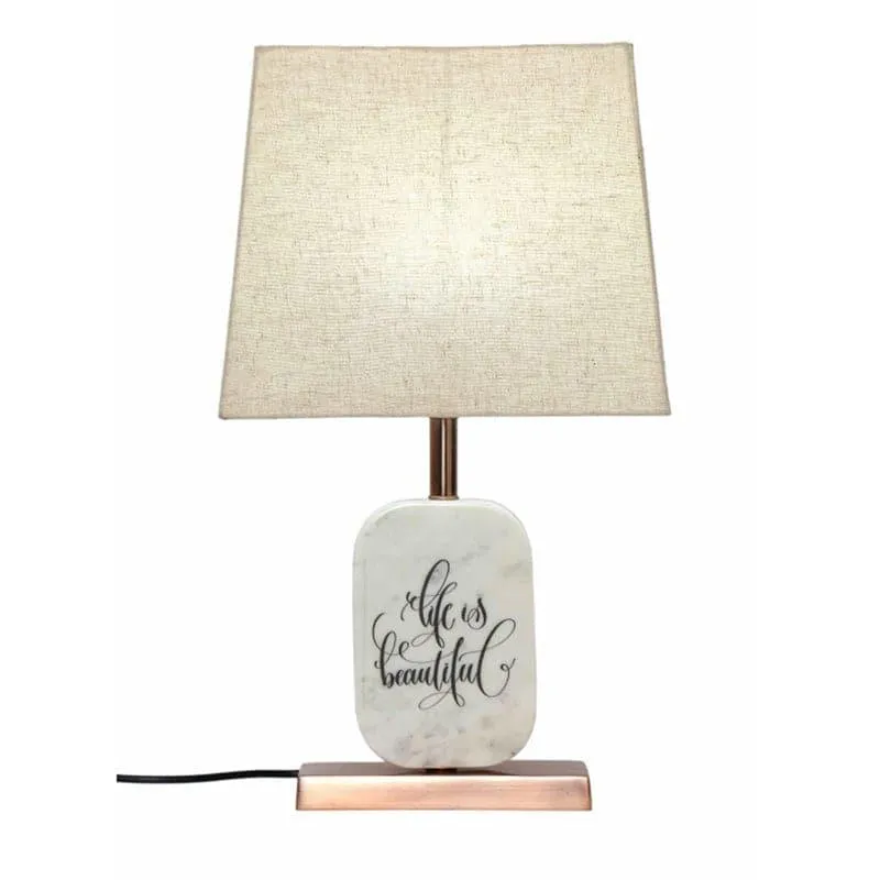 Front view of beige shade table lamp with marble base and script motif