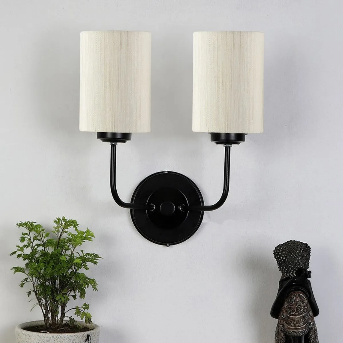 Front view of twin wall lamp with white shades and black iron arms