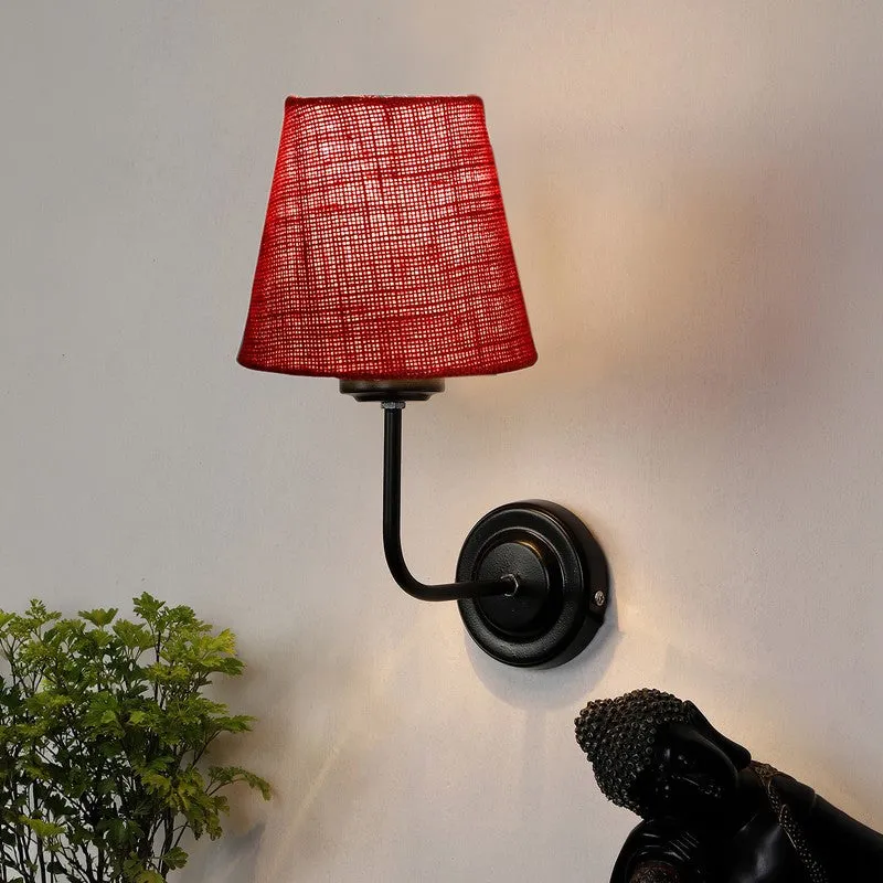 Lit red jute wall lamp with black iron arm on a wall
