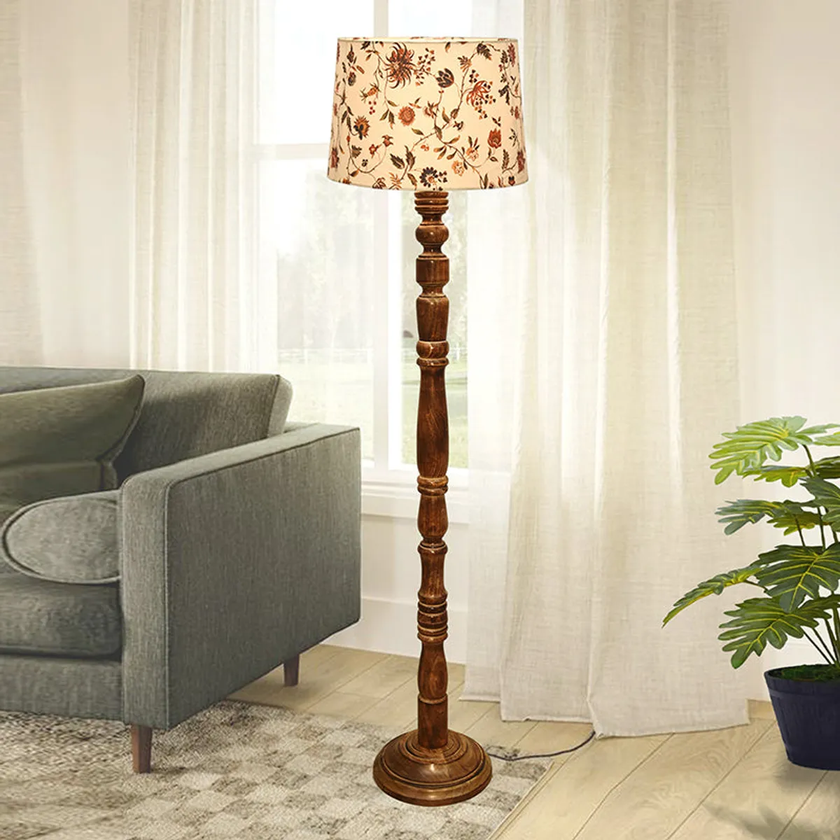 Wooden floor lamp with floral fabric shade beside a grey sofa