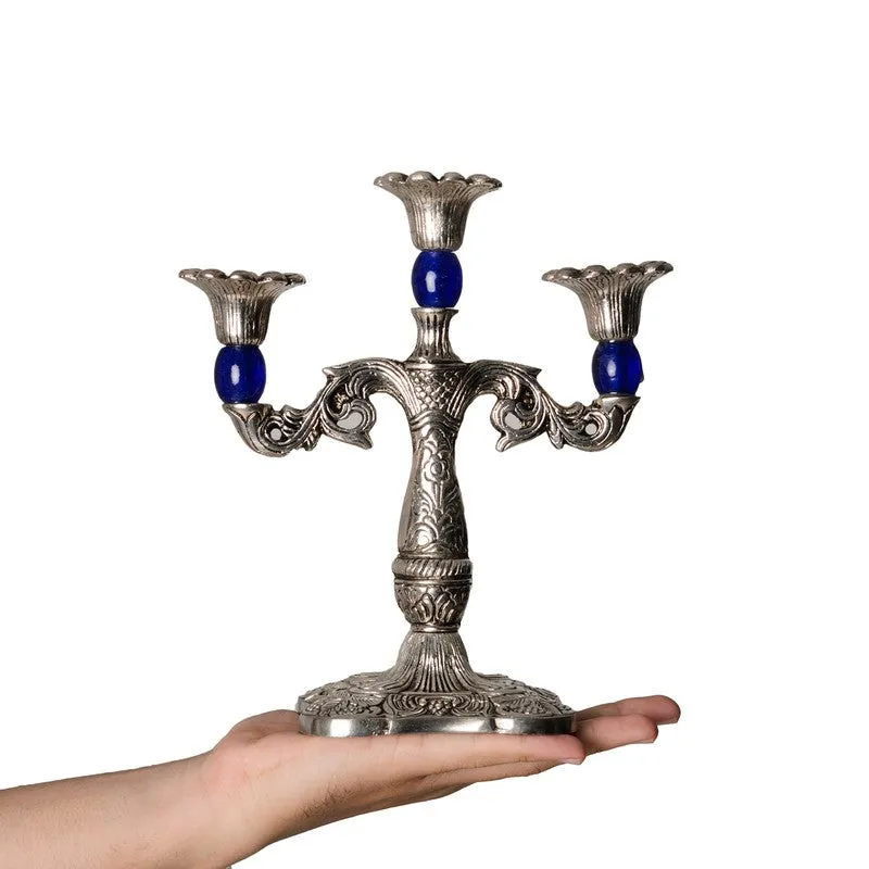 Silver-toned candle holder with blue accents shown resting on a hand