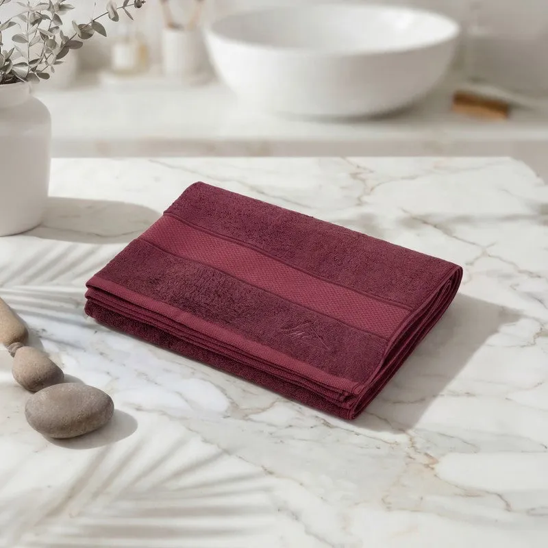 Folded maroon bath towel placed on a marble surface