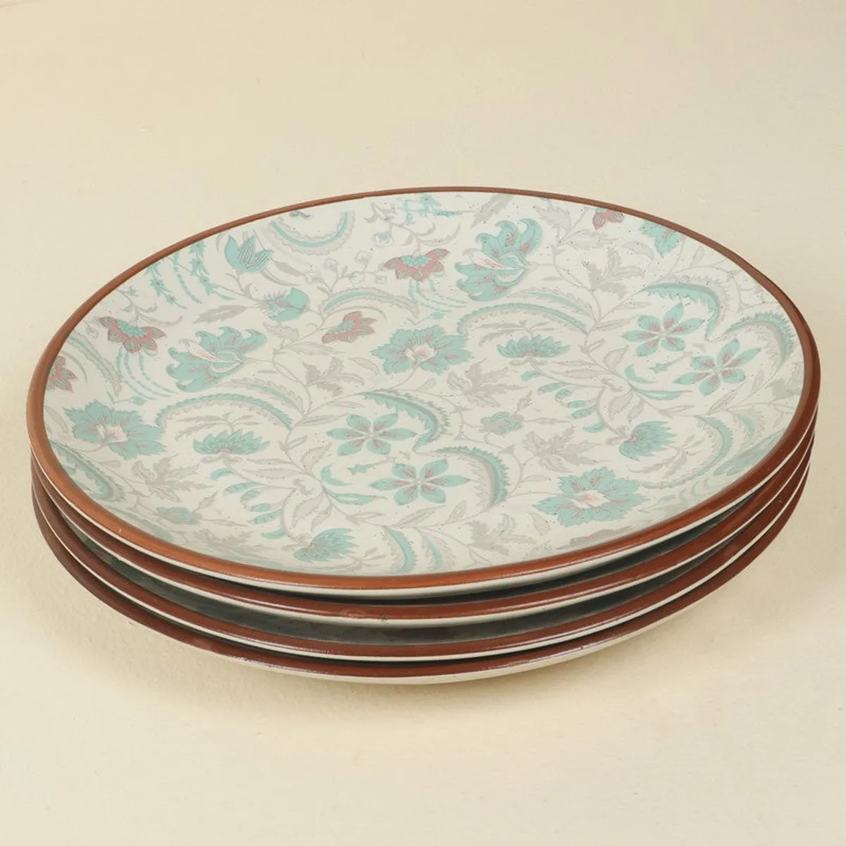Stack of round patterned plates displaying pastel floral motifs and brown rims.