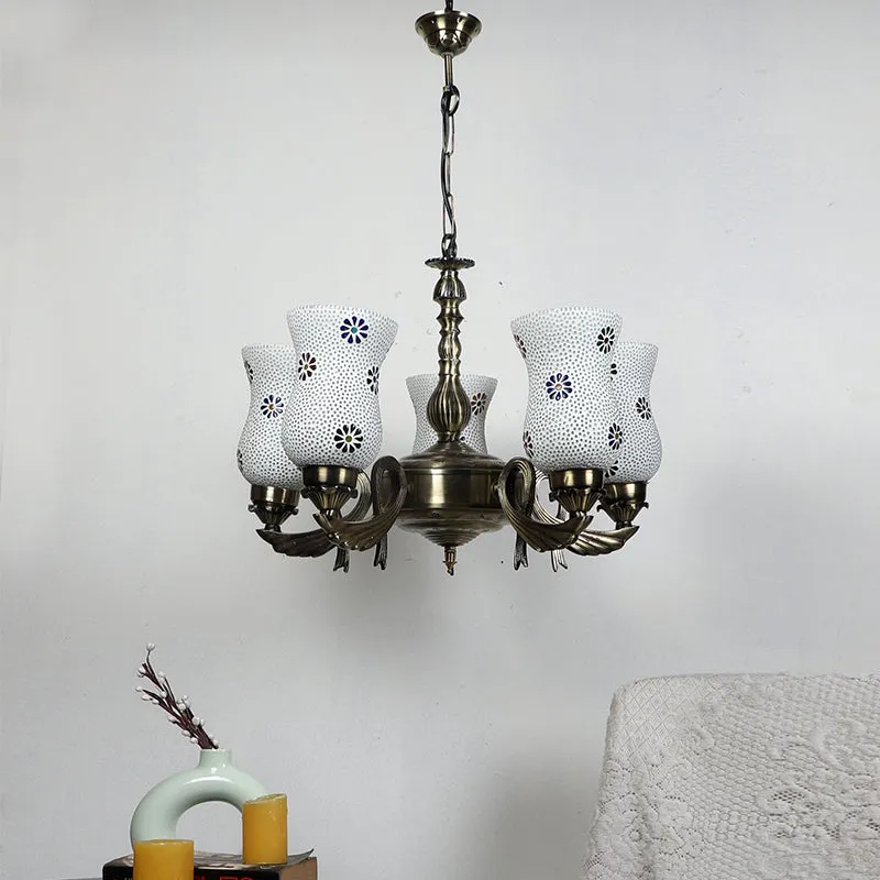 Antique gold ceiling lamp with five white mosaic glass shades against a wall