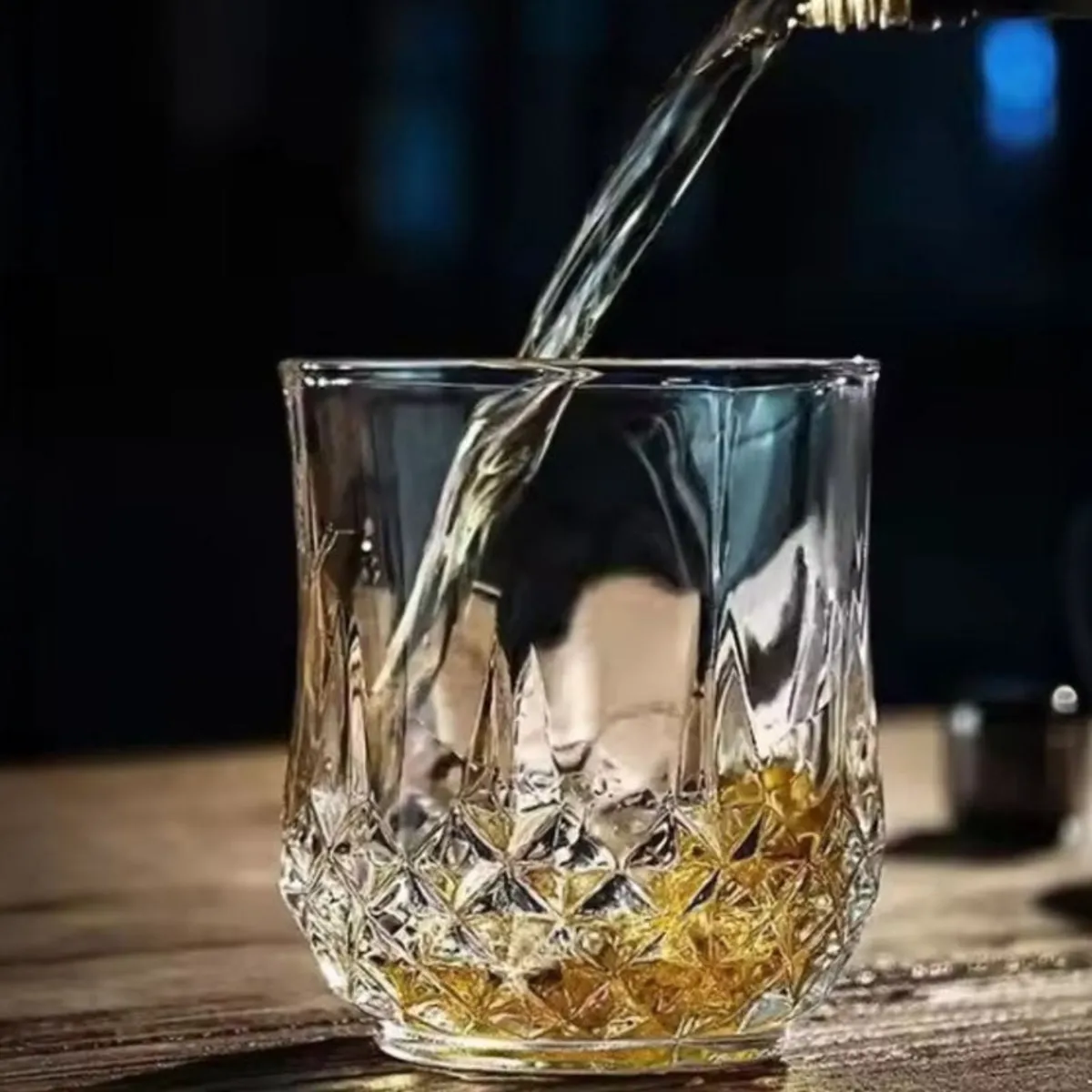 Clear whisky glass with geometric cut detailing being filled with a drink