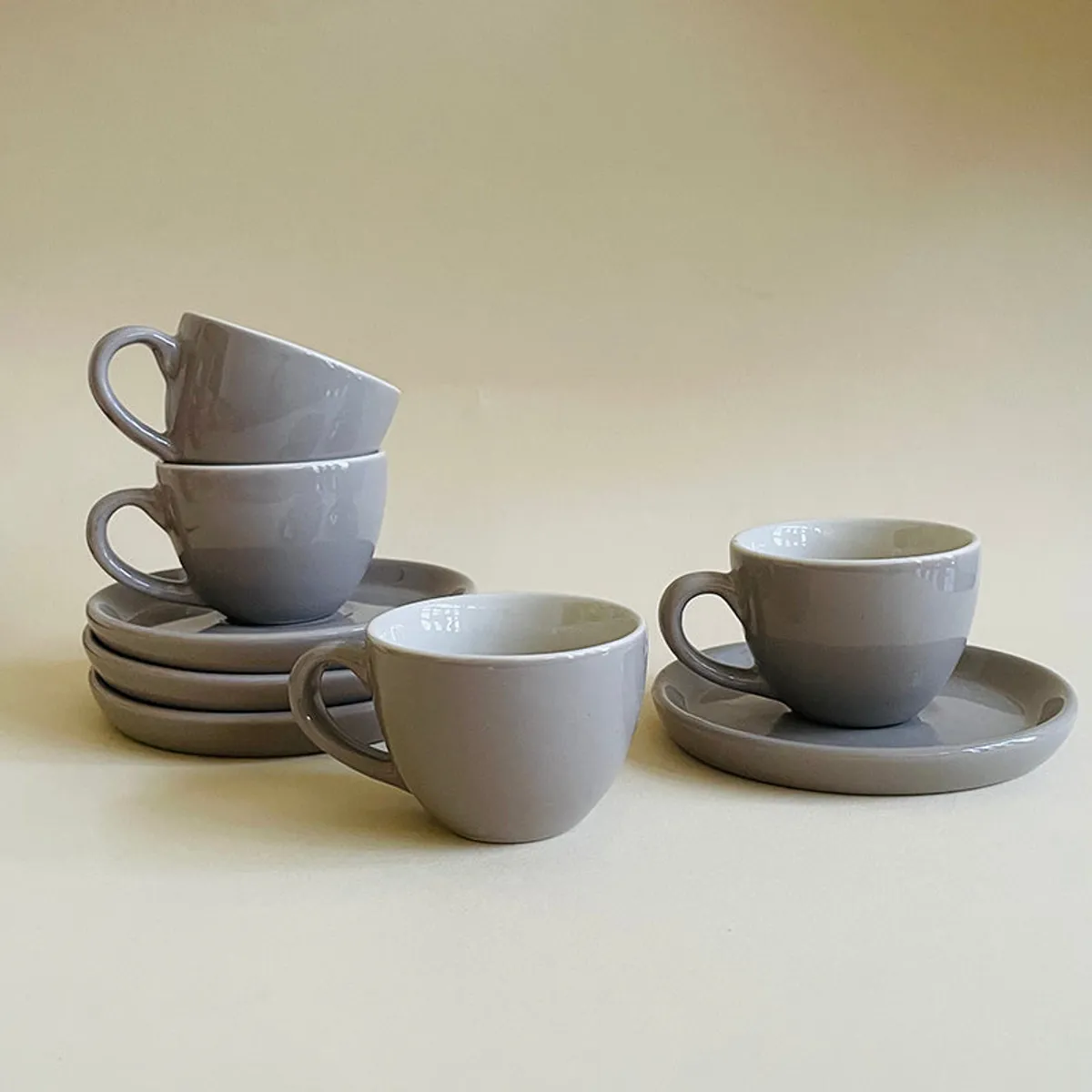 Four grey cup and saucer pieces styled in stacked and paired groups