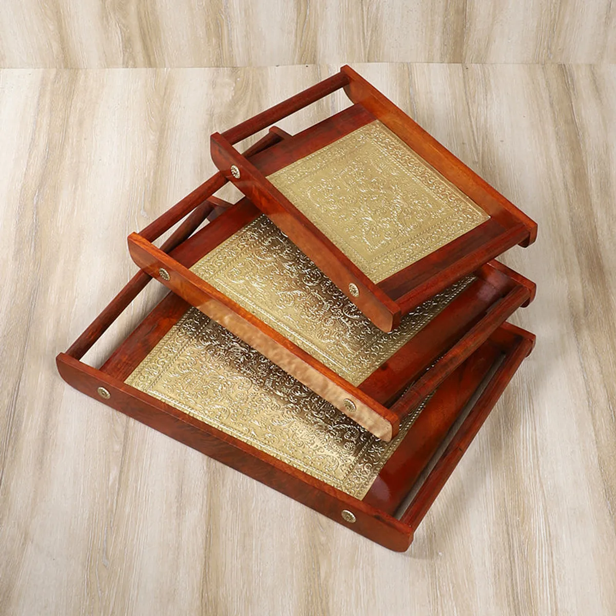 Three rectangular brown trays with gold patterned centres stacked at different angles