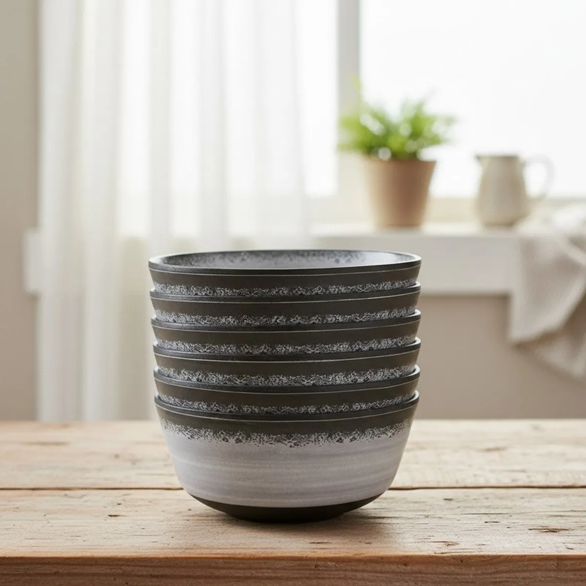 Six stacked black and grey snack bowls on a wooden surface