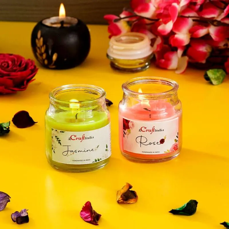 Two lit jar candles in green and pink glass jars on a yellow surface