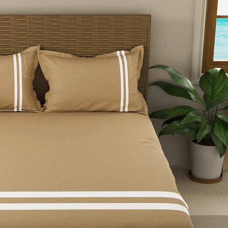 Close view of tan bedsheet with white striped pillow covers