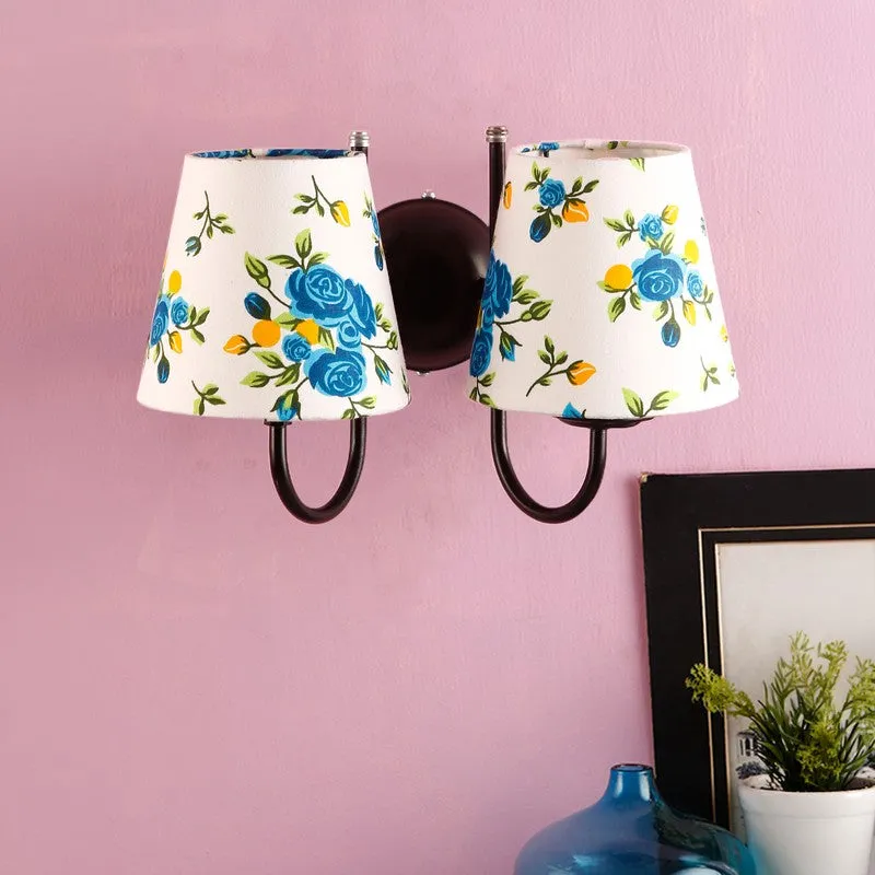 Blue floral double-shade wall lamp against a pink wall