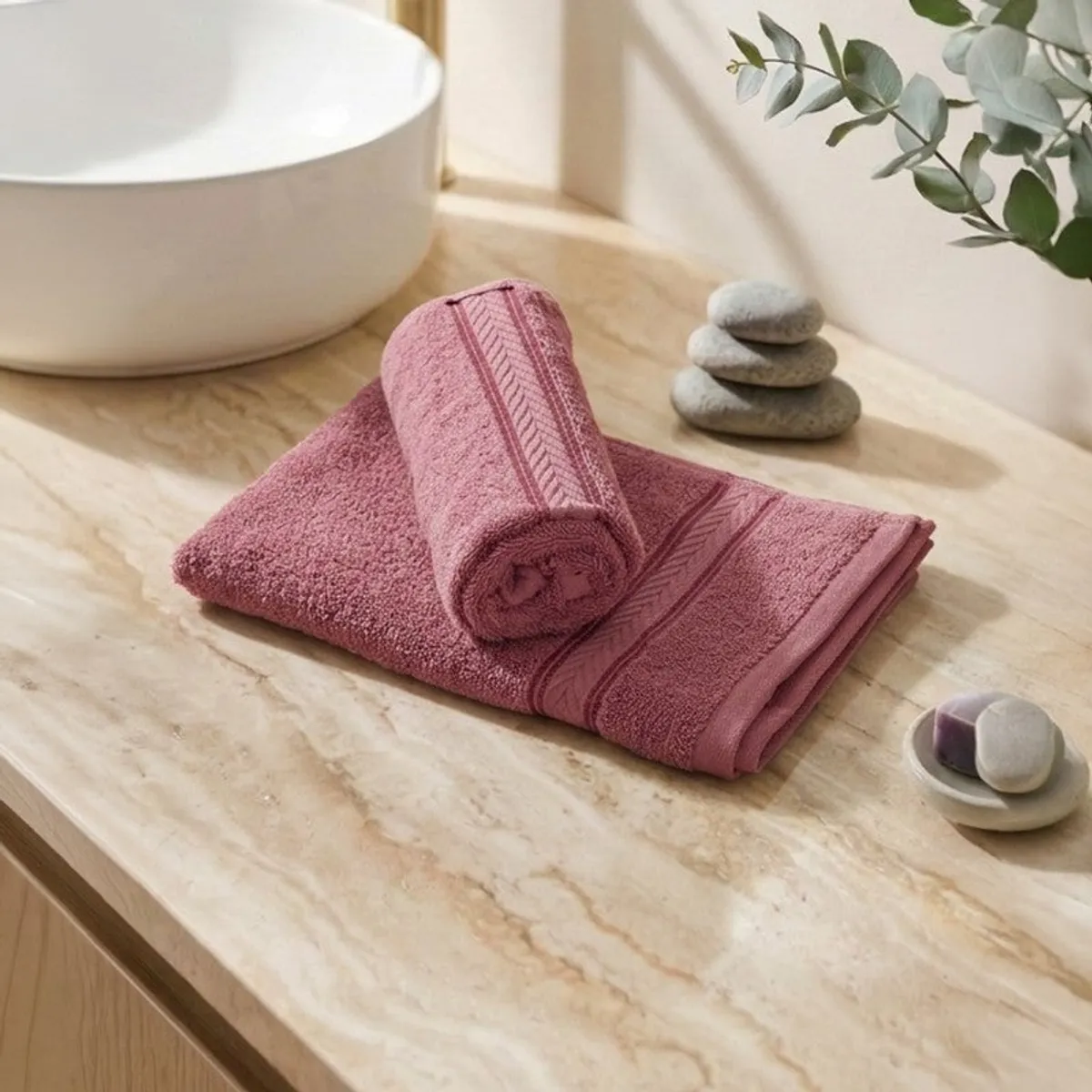Folded dusty pink hand towels arranged on a bathroom counter