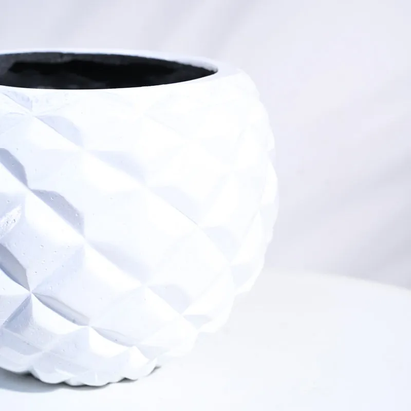 Close-up view of the white planter's raised geometric surface and open rim.