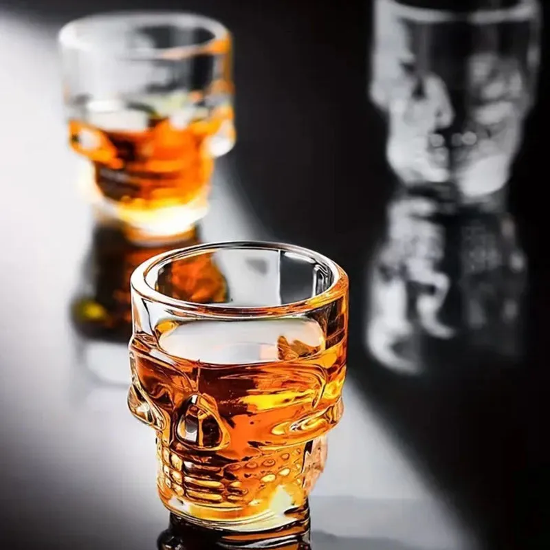 Close-up of a clear skull shot glass filled with an amber drink