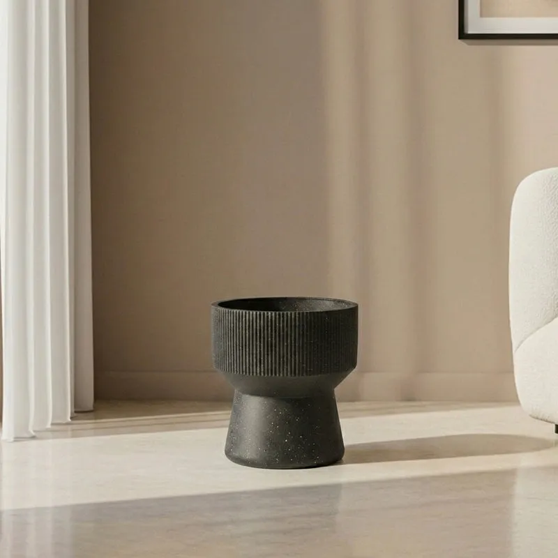 Empty black ribbed pedestal planter shown on a neutral living room floor.