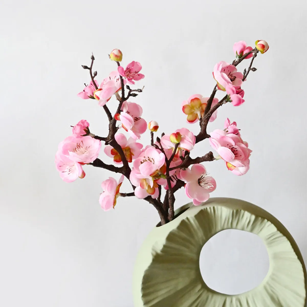 Two pink plum blossom sticks arranged in a decorative vase